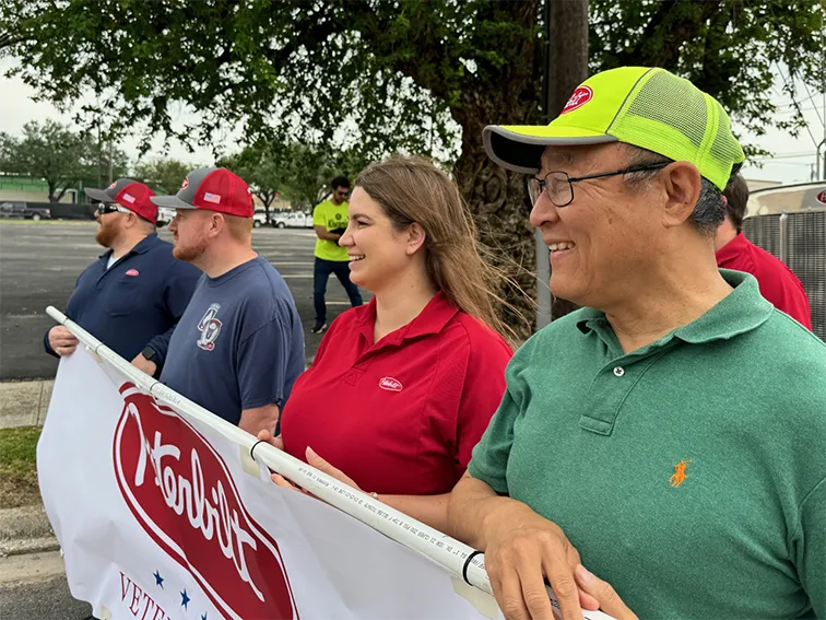 Veteran Peterbilt employees holding banner marching in parade